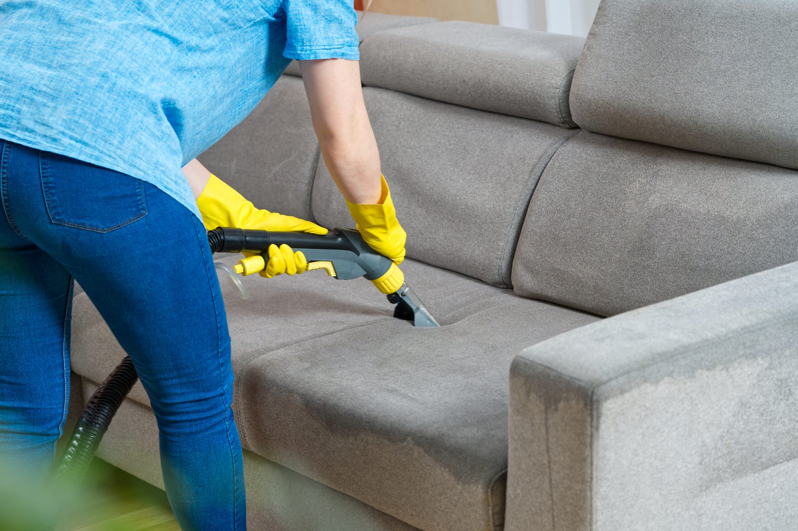 Sofa chemical cleaning with professionally extraction method. Wet textile sofa cleaning. home cleaning service. cleaning sofa with washing suction cleaner closeup.